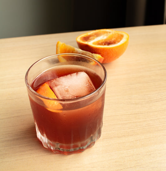 Blood orange cold brew negroni in a cocktail glass with half an orange in the background